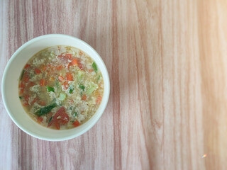A bowl of egg soup on the wooden table. Soft focus. Negative space