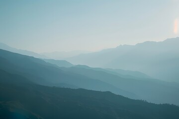 A tranquil view of layered mountains in soft blue hues.