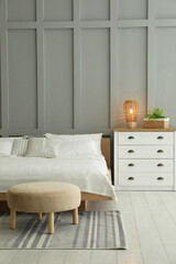 Stylish bedroom interior with comfortable bed, lamp and houseplant
