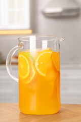 Freshly made lemonade in jug on wooden table in kitchen