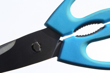 Pair of scissors with blue handles and stainless steel blades on a white background abstract close-up