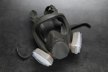 One full face respirator on dark textured table, top view