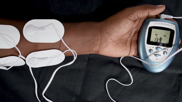 Electric massage procedure in physiotherapy, Electrical frequency therapy electrodes in hands. alternative medicine Electrotherapy, electrical stimulation using surface electrode pads, close up hands