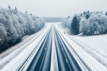 Fototapeta premium Empty highway leading through a snowy winter landscape, with trees and fields blanketed in white, capturing the serenity and quiet of winter travel 
