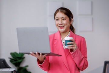 Image of asian business woman wearing pink suit jacket and posing in workplace office. 