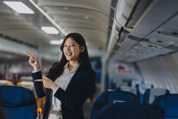 Businesswoman, confident tourist walks with suitcase, checks seat, flight number, puts her suitcase on shelf inside airplane travel lifestyle concept.