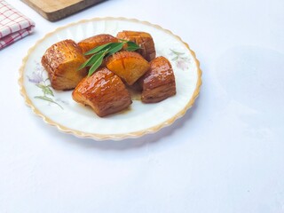Boiled Cassava with Palm Sugar, is a traditional Indonesian dessert made from boiled cassava, combining the sweetness of brown sugar and the soft texture of cassava. Served on a white background.