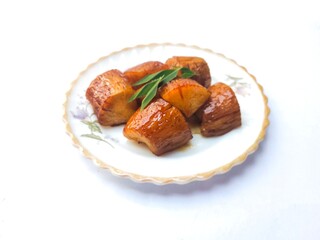 Boiled Cassava with Palm Sugar, is a traditional Indonesian dessert made from boiled cassava, combining the sweetness of brown sugar and the soft texture of cassava. Served on a white background.