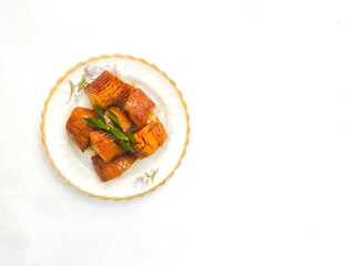 Boiled Cassava with Palm Sugar, is a traditional Indonesian dessert made from boiled cassava, combining the sweetness of brown sugar and the soft texture of cassava. Served on a white background.