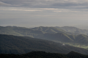 The mountains are covered in trees and the sky is cloudy