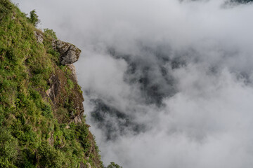 A mountain with a rocky outcropping and a cloudy sky