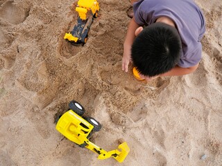 Top view of boy playing with toys on sandy beach