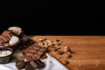 Chocolate chip cookies, dark and white chocolate bar, small bowl of oatmeal and nuts. International Chocolate Day. Copy space.