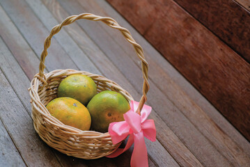 Yellow green orange fruits in basket isolated on wooden background
