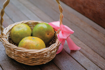 Yellow green orange fruits in basket isolated on wooden background