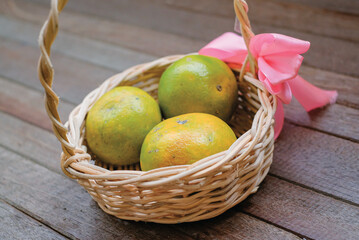 Yellow green orange fruits in basket isolated on wooden background