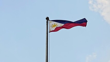 Philippine flag waving in the wind against a blue sky