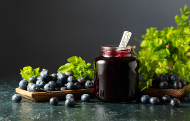 Blueberry jam and fresh berries with leaves.