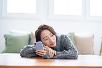 リビングで携帯を持ち笑うショートヘアー女性