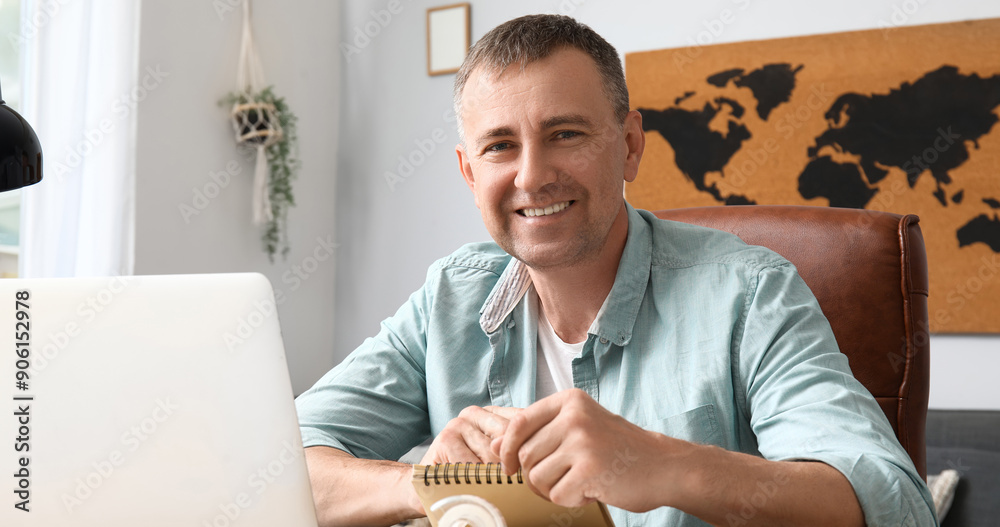 Wall mural mature male freelancer working with notebook at table in office