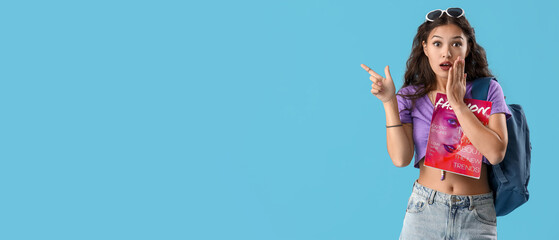 Female Asian gossip student pointing at something on blue background