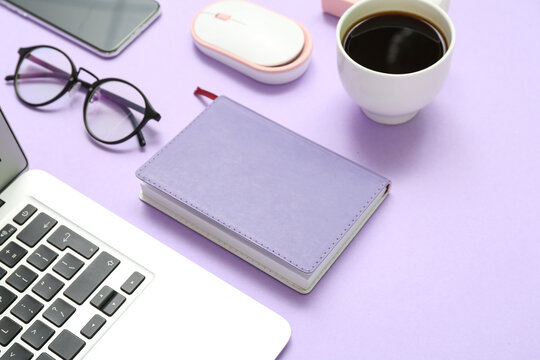 Composition with laptop, coffee, eyeglasses and notepad on purple background - Powered by Adobe