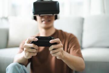 Young Asian man gamer wearing virtual reality touching air during the VR experience  Future home technology player hobby playful enjoyment concept.