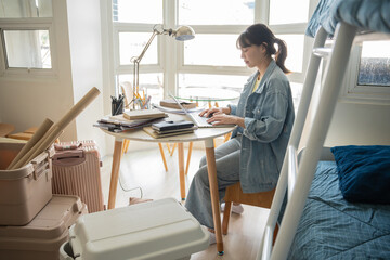 asian girl sit chair table work laptop. messy room