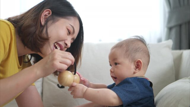 A tiny child smiling happily on the couch in the living room with mom