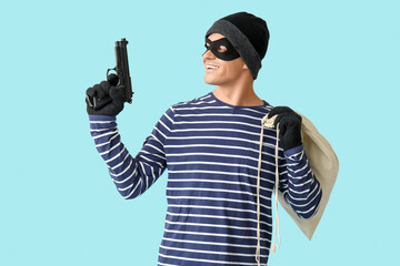 Male thief with gun and bag on blue background