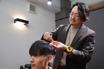 Fototapeta premium 髪を切る男性美容師