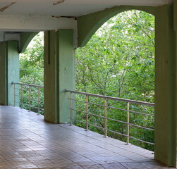 A balcony with railings and a canopy overlooking the green garden