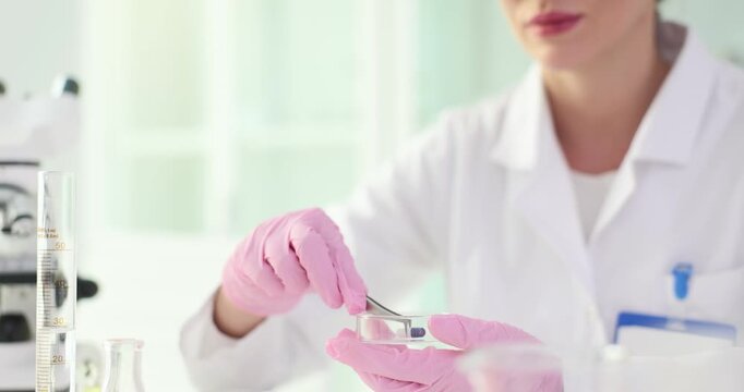 Woman researcher examines shape and size of tablet. Qualified scientist in white lab coat prepares to study composition of pill slow motion