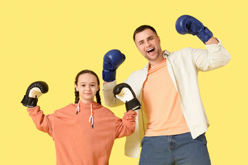 Father and his daughter in boxing gloves on yellow background