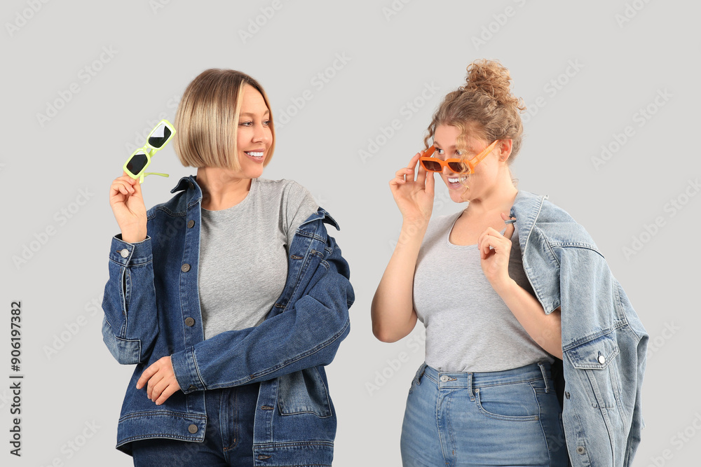 Canvas Prints Beautiful happy women in stylish jeans with sunglasses on grey background