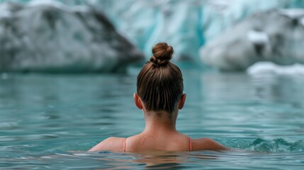 Fototapeta premium Behind the scenes, a young woman takes a bath to acclimate herself in winter, blurred amidst snow-covered mountains.