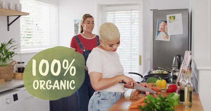 Image of 100 percent organic text over diverse female couple cooking at home