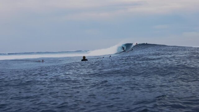 Slow motion wide angle view of surfer riding wave at Cloudbreak Fiji