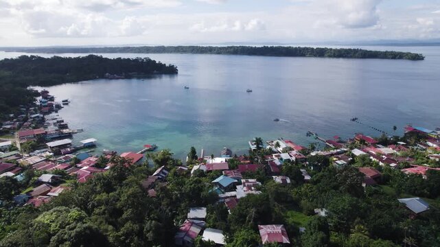 Aerial view of Bastimentos Islands' picturesque coastline in Panama, featuring vibrant homes and lush greenery by the water. orbit motion shot
