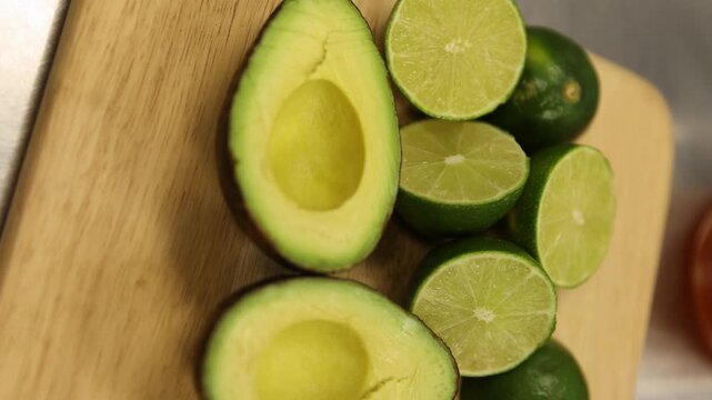 Avocados And Limes Cut In Halves On A Wooden Chopping Board. Close Up Studio Shot.