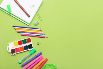 Pencils and felt-tip pens on green background. Top view