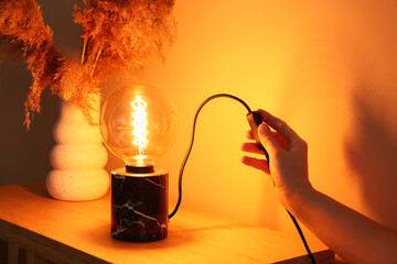 Woman turning on glowing lamp, closeup