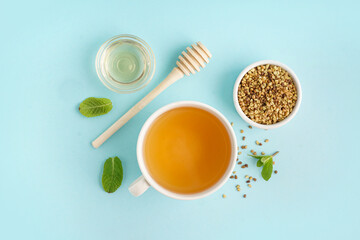 Cup of tasty buckwheat tea, honey and mint on blue background