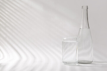 Bottle of clean water and glass on white background