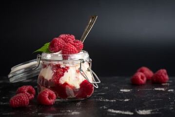 Mason jar filled with layered dessert, topped with fresh raspberries and mint.