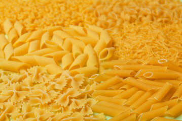 Different types of delicious uncooked pasta on table, closeup