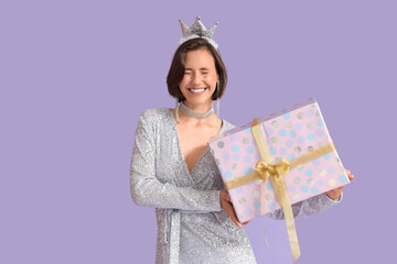 Beautiful woman in crown with Birthday gift on lilac background