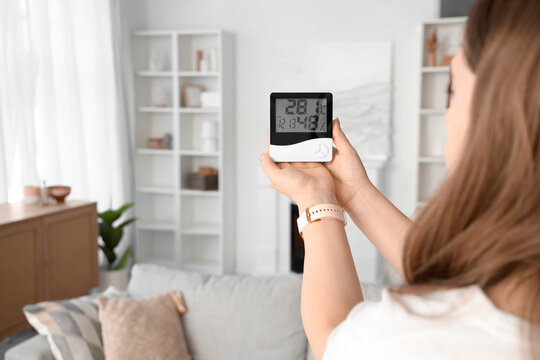 Woman with digital hygrometer at home, closeup