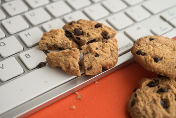 Broken chocolate chip cookies on keyboard computer background. Cookies website internet homepage policy accpeted or blocks, technology internet website concept.