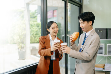 Happy two Asian business holding coffee cup in modern office.
